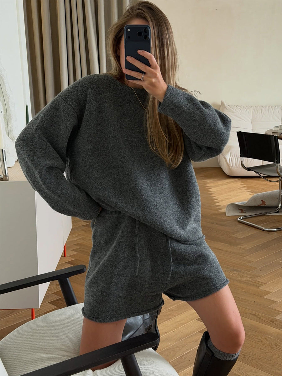 Women’s dark gray oversized knit pullover with drawstring shorts set, hands on hips