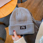 Light gray ribbed knit beanie with folded cuff and woven brand patch.