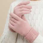 Pink knit gloves with ribbed fold-over cuffs and bow embroidery, worn on hands