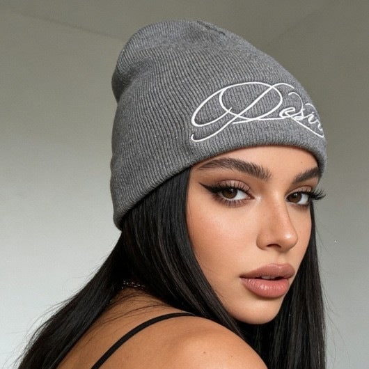 Gray ribbed knit beanie with white embroidered script lettering on the front.