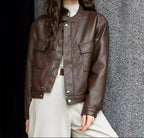 Brown cropped faux leather jacket with band collar, snap placket, and flap pockets