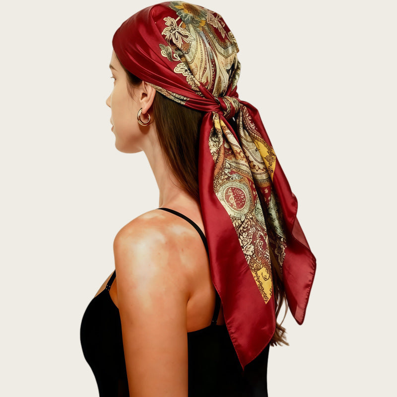 Satin head scarf in deep burgundy with gold paisley print, tied at back.