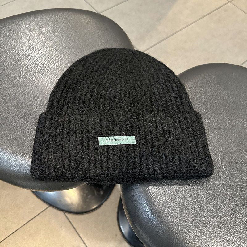Black ribbed knit beanie with wide cuff and woven "pipiswoot" label