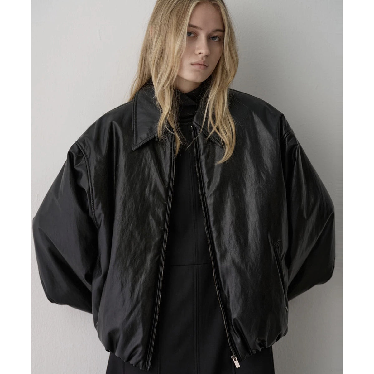 Black faux leather bomber jacket close-up: point collar and zip front