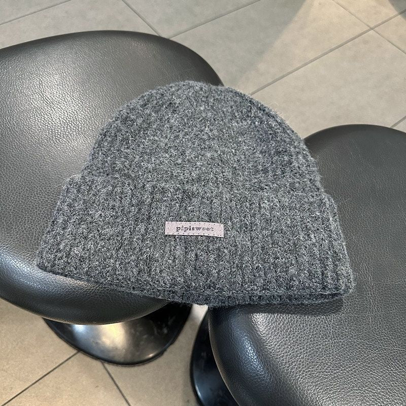 Dark gray fuzzy knit beanie with woven "pipiswoot" label