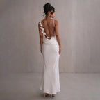 White satin maxi dress with backless design and lace-trim rosette straps.