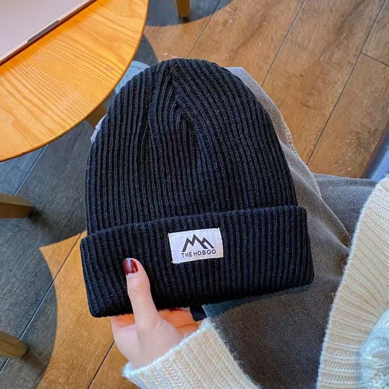 Navy ribbed knit beanie with folded cuff and woven brand patch.