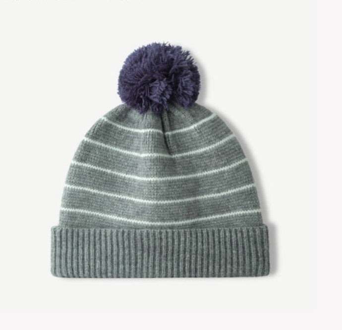 Green striped knit beanie with fluffy navy pom-pom and ribbed cuff