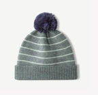 Green striped knit beanie with fluffy navy pom-pom and ribbed cuff