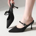 Black pointed-toe Mary Jane mule on foot with stiletto heel and buckle strap