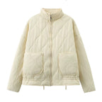 Off-white quilted stand-collar zip-up jacket with long sleeves and two flap chest pockets.