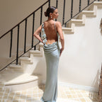 Light green satin maxi dress with backless design and rosette strap detail.