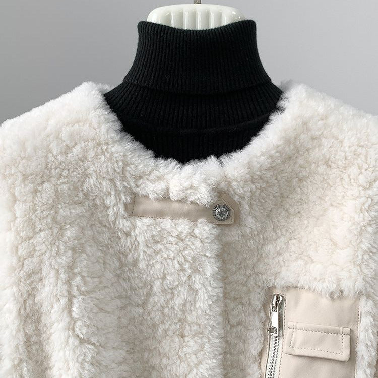 Detail of the jacket's collarless neckline, snap tab, and zip chest pocket.