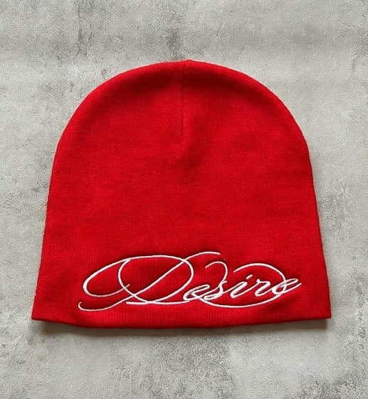 Red knit beanie with white embroidered script lettering, flat lay front view.