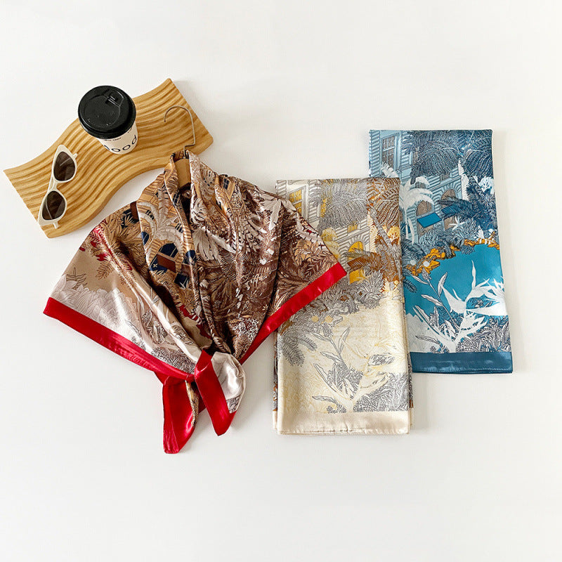 Tropical floral satin square scarves folded, in blue, beige, and brown.