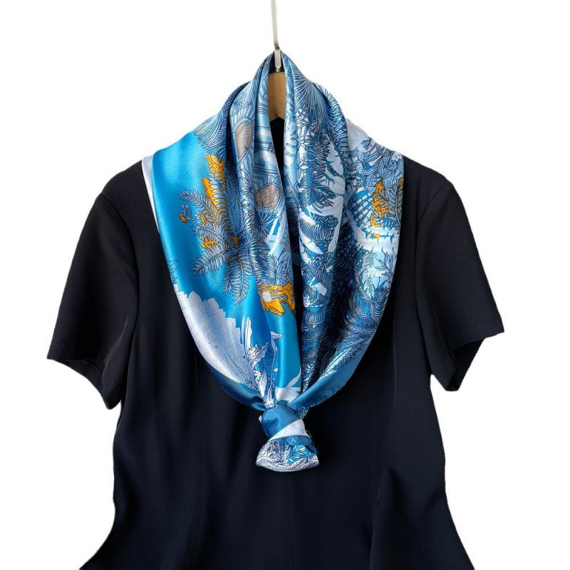 Blue satin square scarf with tropical floral print, neatly knotted at the neck.