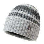 Striped knit beanie in gray with dark stripes and metal badge on cuff