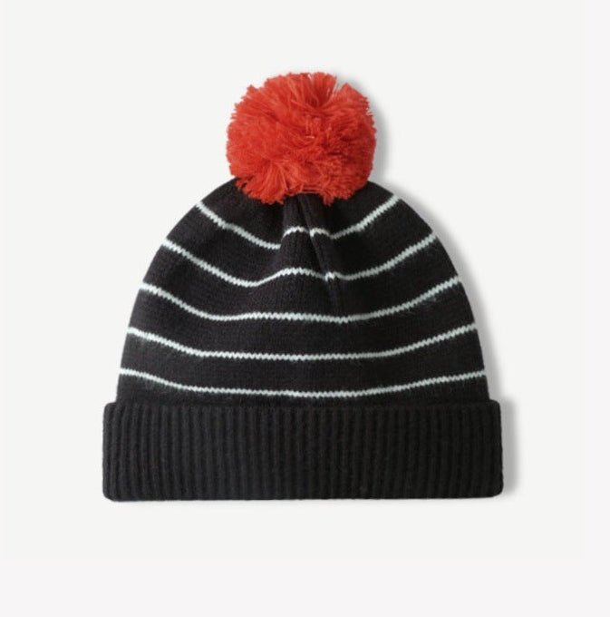 Black-and-white striped knit beanie with fluffy red pom-pom and ribbed cuff
