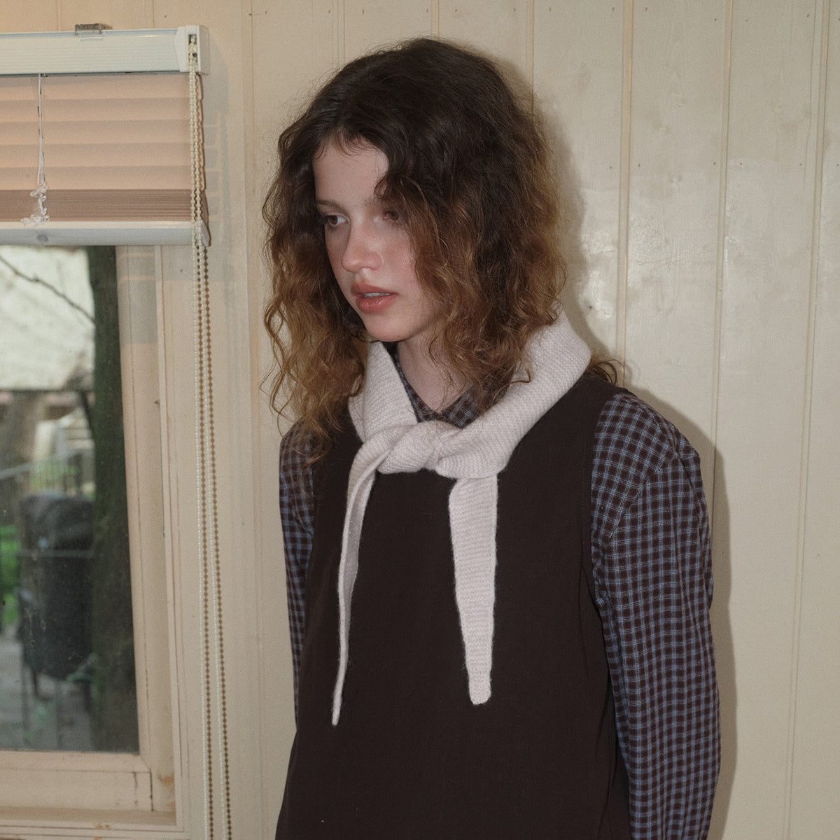 Beige wool knit skinny scarf with pointed ends, worn as a neck scarf with ties.