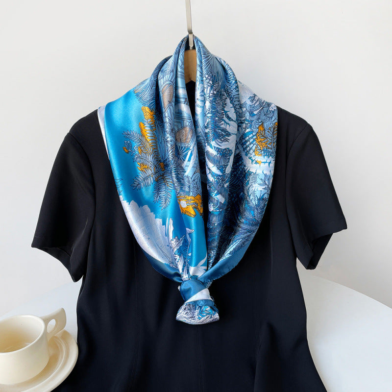 Blue satin square scarf with tropical floral print, styled in a knotted neck wrap.