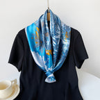 Blue satin square scarf with tropical floral print, styled in a knotted neck wrap.