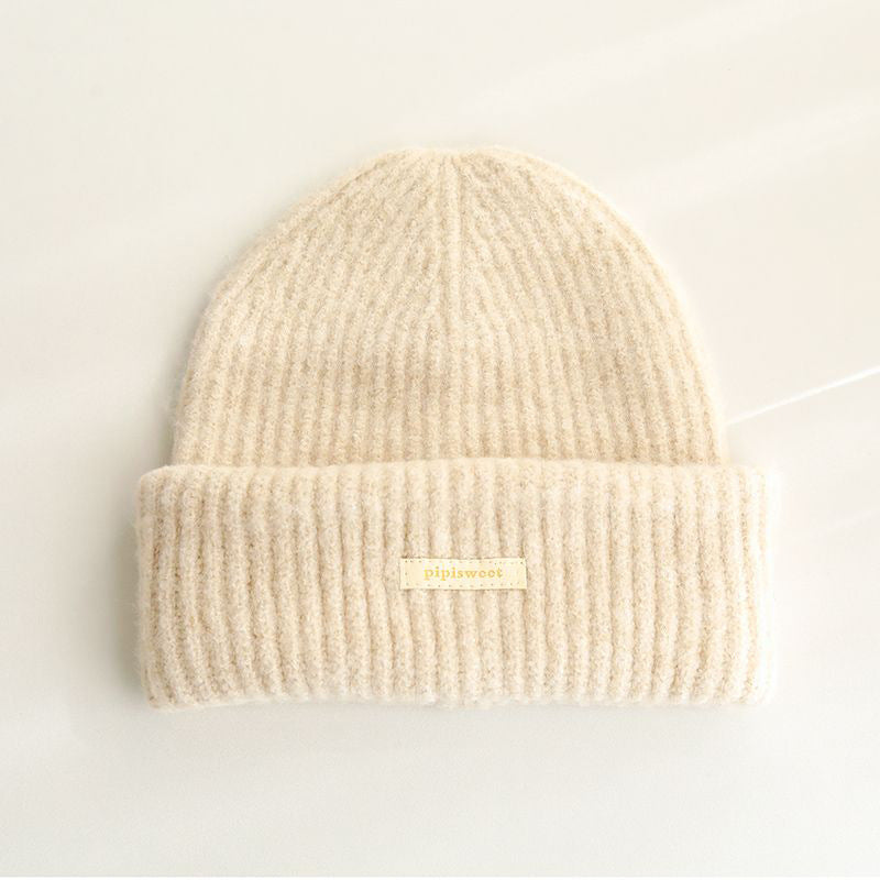 Beige ribbed knit beanie with wide cuff and woven "pipiswoot" label