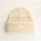 Beige ribbed knit beanie with wide cuff and woven "pipiswoot" label