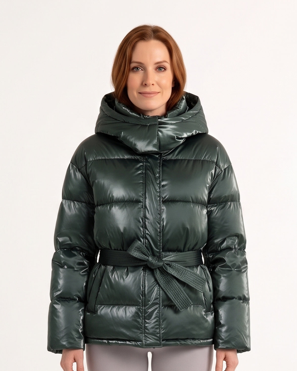 Women’s belted puffer jacket in glossy dark green with oversized hood and tie waist
