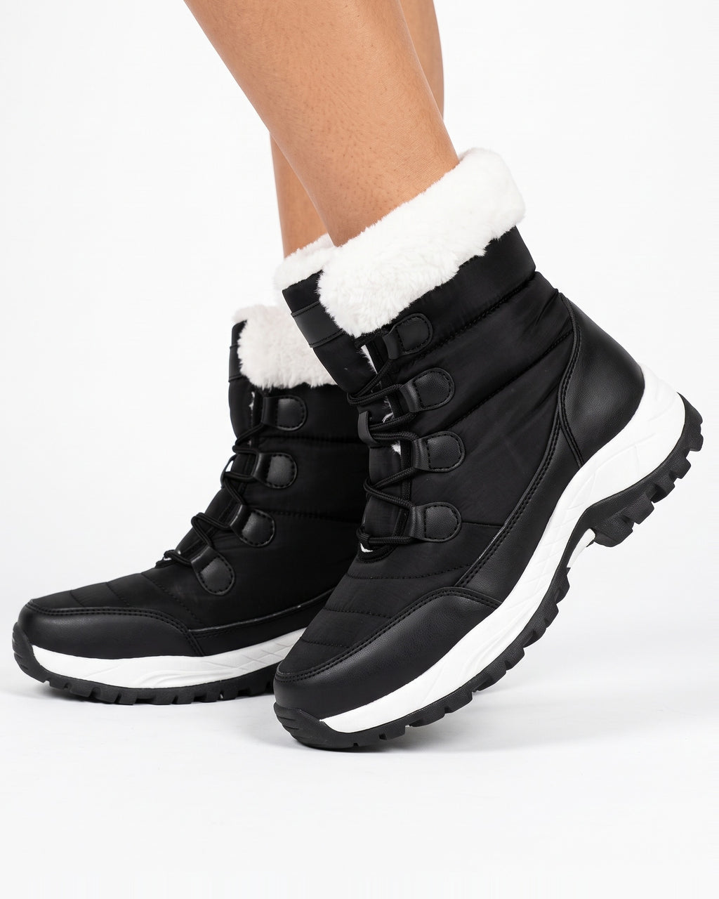 Women’s black faux fur lined lace-up snow boots on model, side view with lug sole.