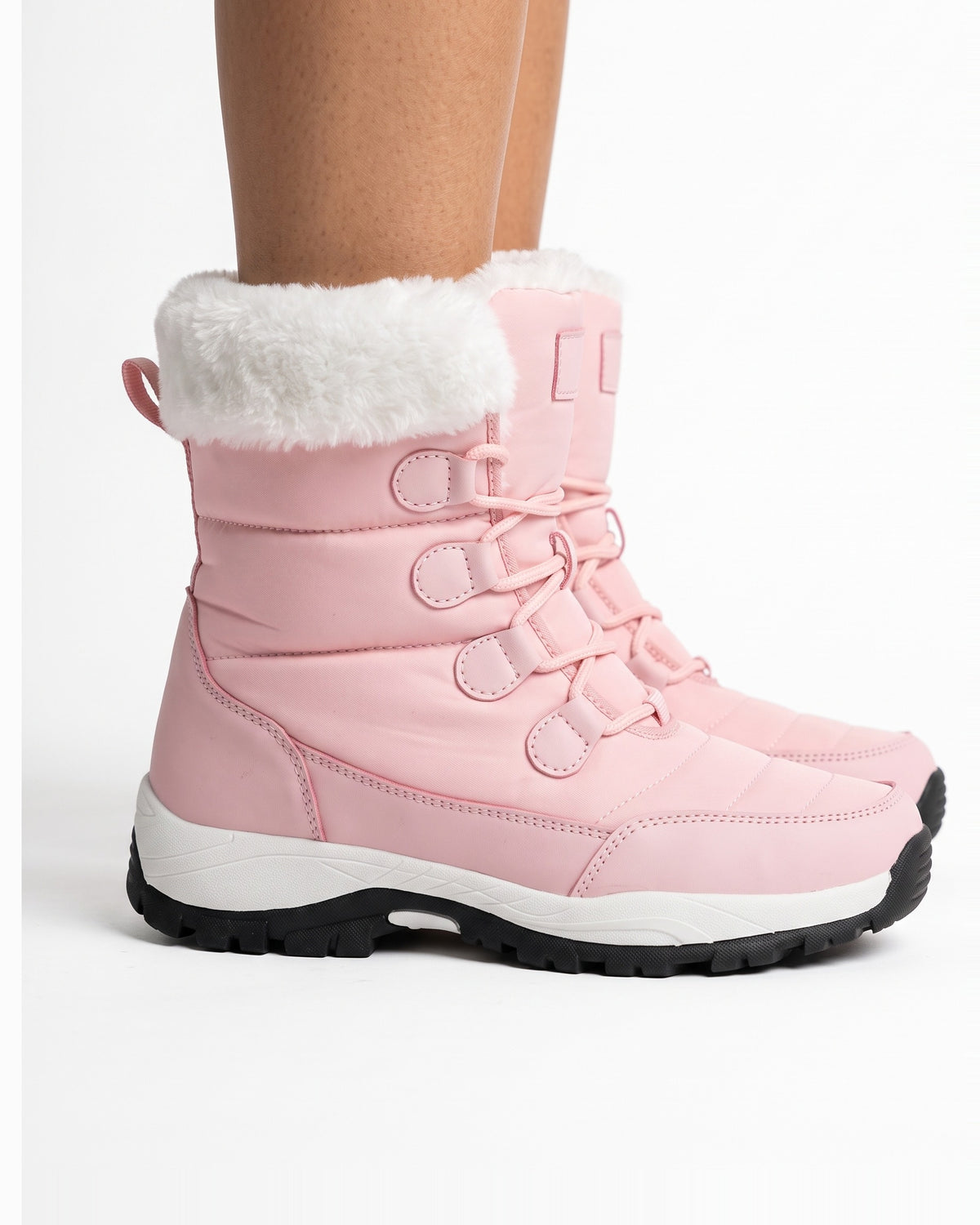 Women’s pink faux fur lined lace-up snow boots on model, side view with lug sole.