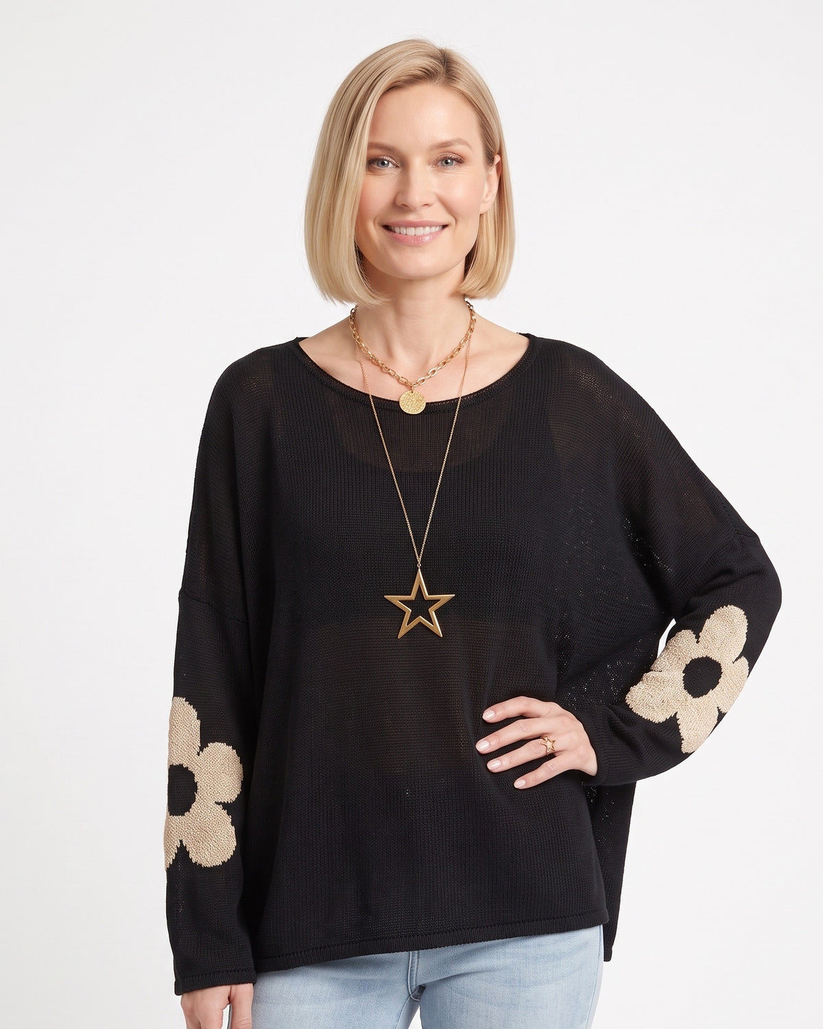 Black oversized knit sweater with beige flower motifs on sleeves