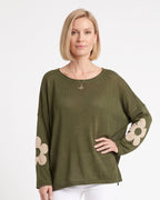 Women's olive green oversized knit sweater with beige flower motifs on the sleeves