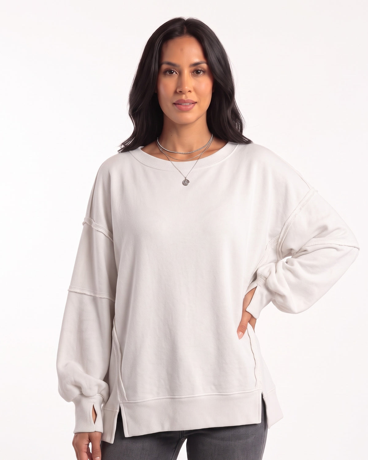 White oversized sweatshirt with exposed seams, long cuffs, and side slits