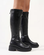 Black knee-high platform boots with chunky lug sole and block heel, faux leather