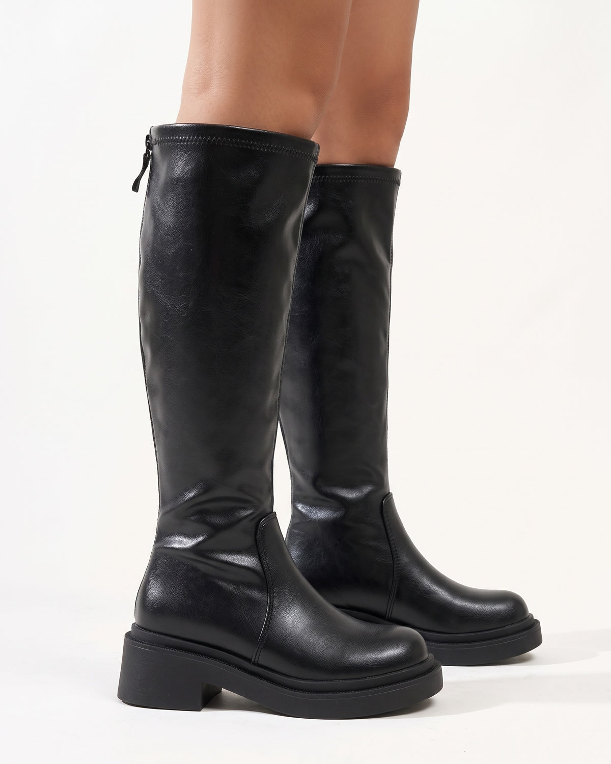 Black knee-high platform boots with chunky lug sole and block heel, faux leather