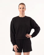 Black crew neck sweatshirt with matching drawstring lounge shorts on a model.