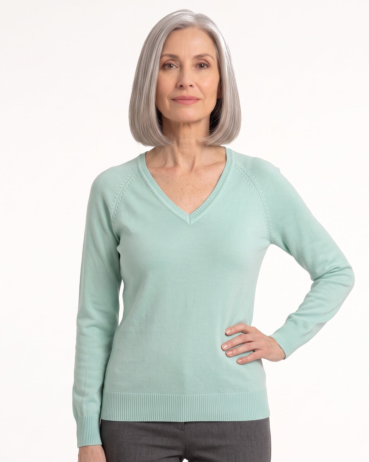 Women’s mint green V-neck fine-knit sweater with long sleeves, worn with dark pants